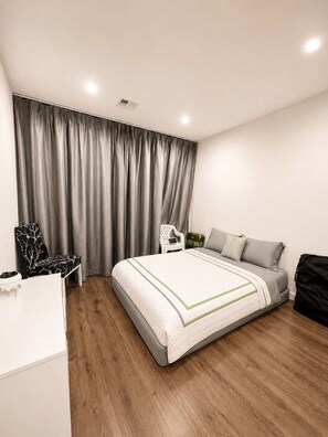 A modern bedroom with a bed, a desk, a chair, and a wardrobe.