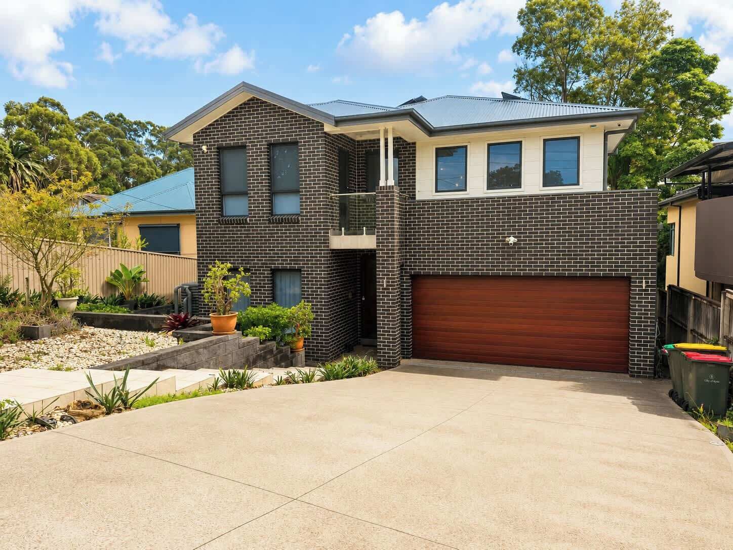 A two-story house with a garage, a balcony, and a driveway.