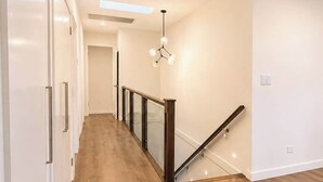 Um interior moderno com piso de madeira, guarda-corpo de vidro e escada.