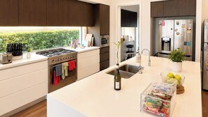 Uma cozinha moderna com ilha central, eletrodomésticos embutidos e vista para o verde lá fora.