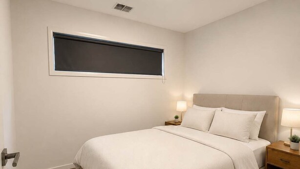 Quarto com cama, mesas de cabeceira, janela e luminária no teto.