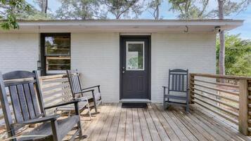 Une terrasse en bois avec deux chaises et une porte.