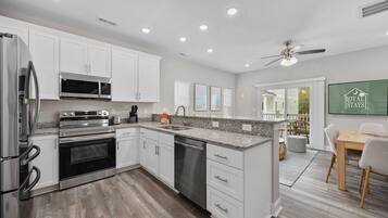 A modern kitchen with white cabinetry, stainless steel appliances, and a granite countertop.