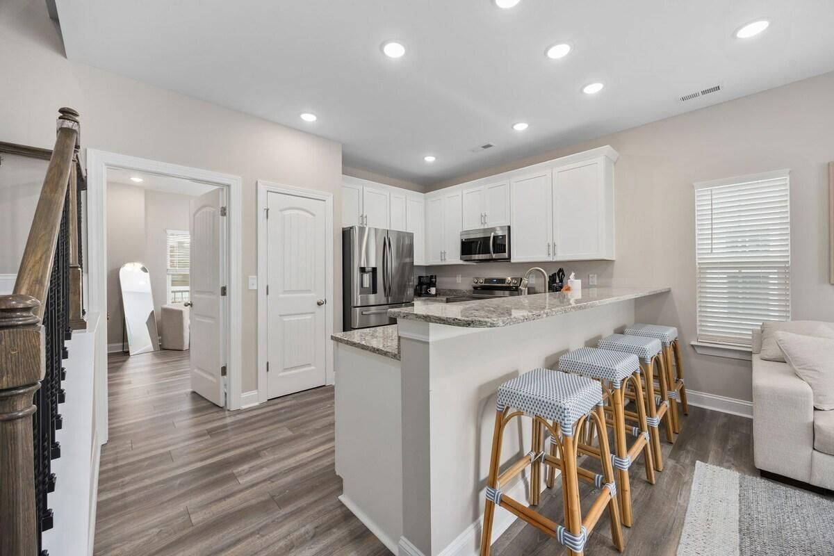 A modern kitchen with white cabinets, stainless steel appliances, and a central island with bar stools.