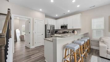 A modern kitchen with white cabinets, stainless steel appliances, and a central island with bar stools.