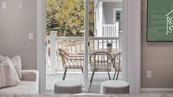 A living room with a sliding glass door leading to a balcony with wicker chairs and ottomans.