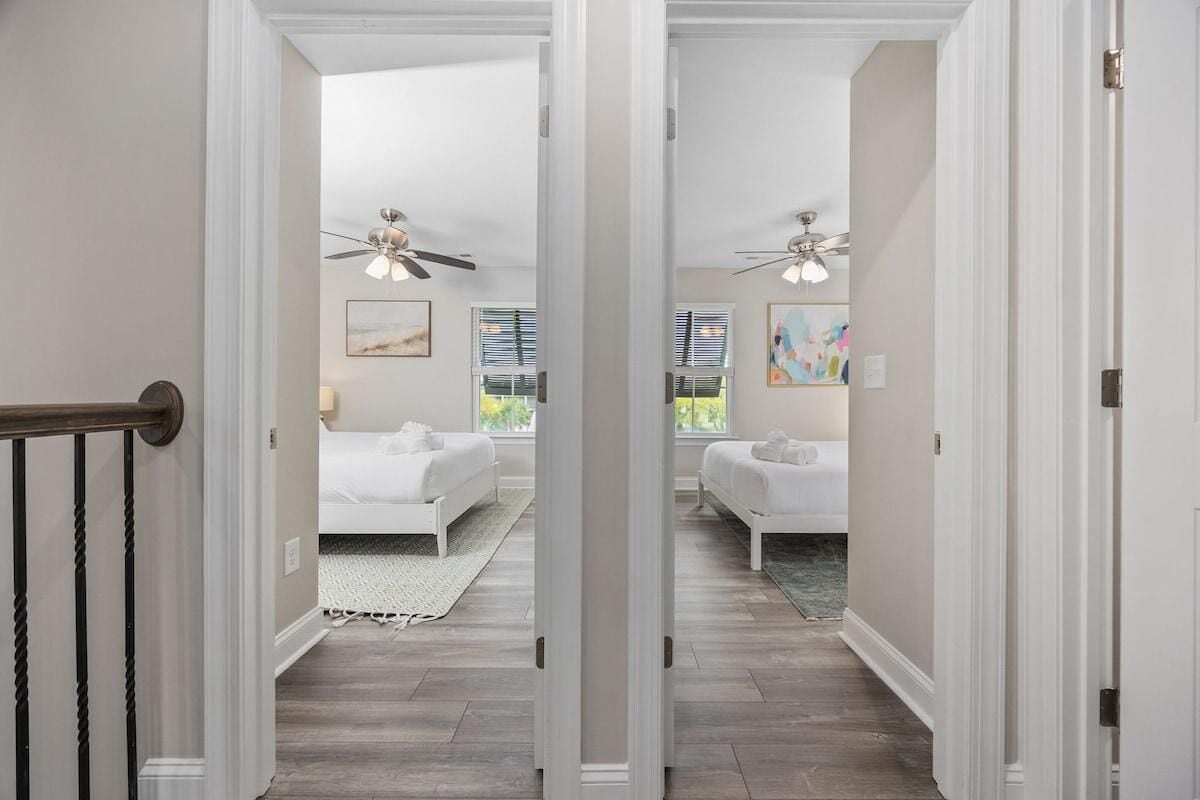 A hallway leading to a bedroom with a bed, a ceiling fan, and artwork on the walls.