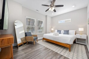 A bedroom with a bed, bedside tables, a chair, a ceiling fan, and a large mirror. - Sea Cloud-across Ocean-pet Friendly! (Myrtle Beach)