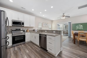 A modern kitchen with white cabinets, stainless steel appliances, and a granite countertop. - Sea Cloud-across Ocean-pet Friendly! (Myrtle Beach)
