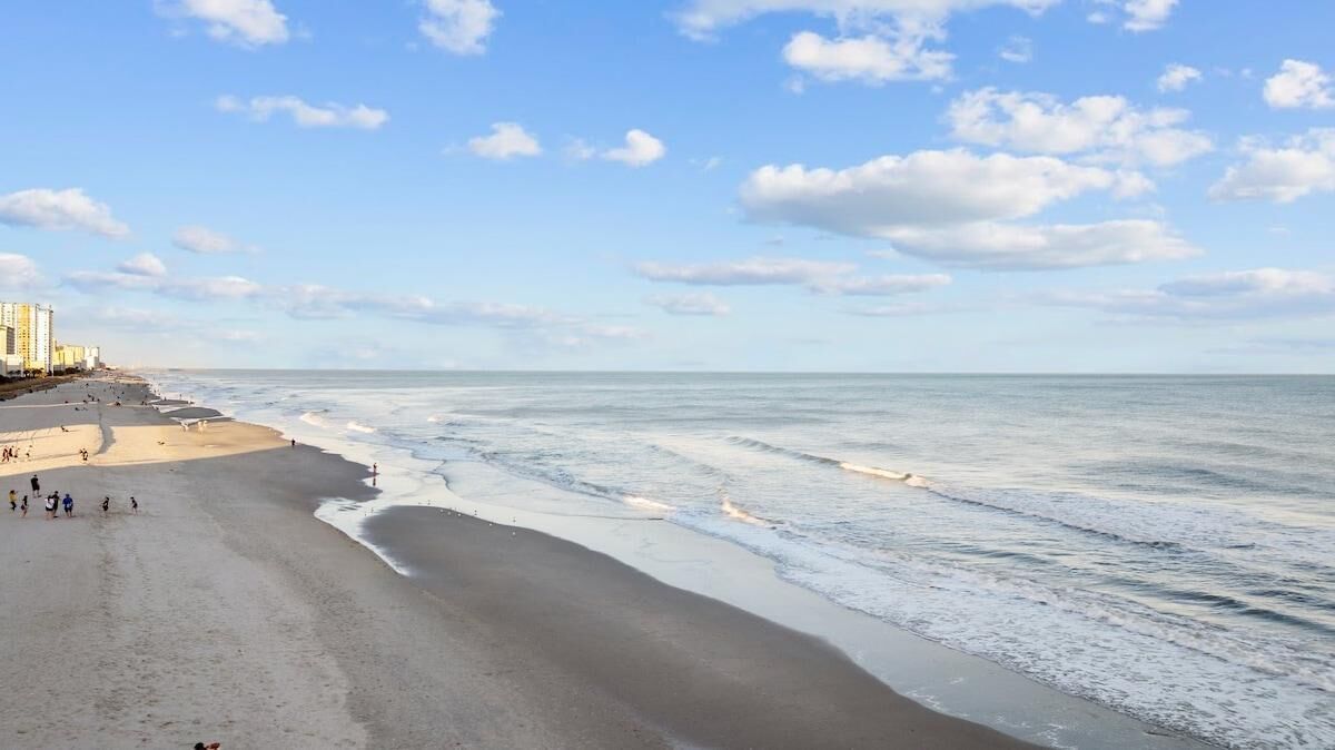 Ein Strand mit sandigem Ufer und blauem Himmel.