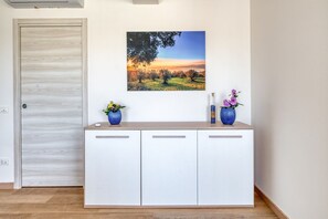 Ein Zimmer mit einem weißen Schrank, einer Tür und einem Landschaftsbild an der Wand.