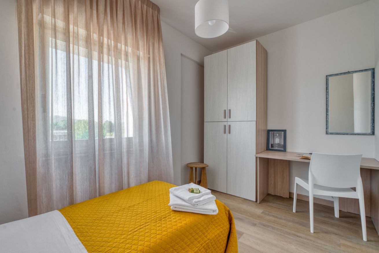 A bedroom with a bed, a desk, a chair, and a wardrobe.