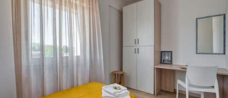 Un dormitorio con cama, escritorio, silla y armario.