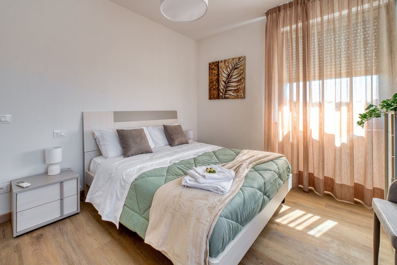 A modern bedroom with a bed, bedside table, and curtains.