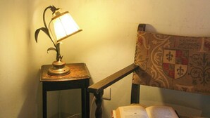 A room with a lamp on a small table, an open book on a chair, and a wall with a tree painting. - Pool villa with panoramic view in Cortona (Sodo)