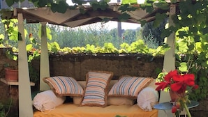 A garden bed with a bench, pillows, and a potted plant. - Pool villa with panoramic view in Cortona (Sodo)