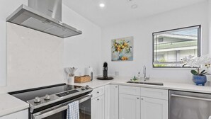 Une cuisine moderne avec des armoires blanches, une cuisinière en acier inoxydable et un four encastré.