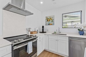 Uma cozinha moderna com armários brancos, fogão de aço inoxidável e forno embutido.