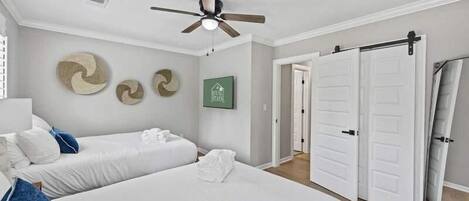 Une chambre avec deux lits, un ventilateur de plafond et un placard à portes coulissantes.