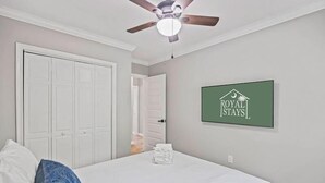 Une chambre à coucher avec un lit, un ventilateur de plafond, une porte et un panneau accroché au mur.