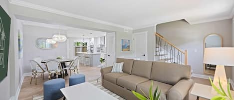 A modern living room with a sofa, coffee table, and dining area.