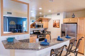 Eine moderne Küche mit Granit-Arbeitsplatten, Edelstahlgeräten und Holzschränken.