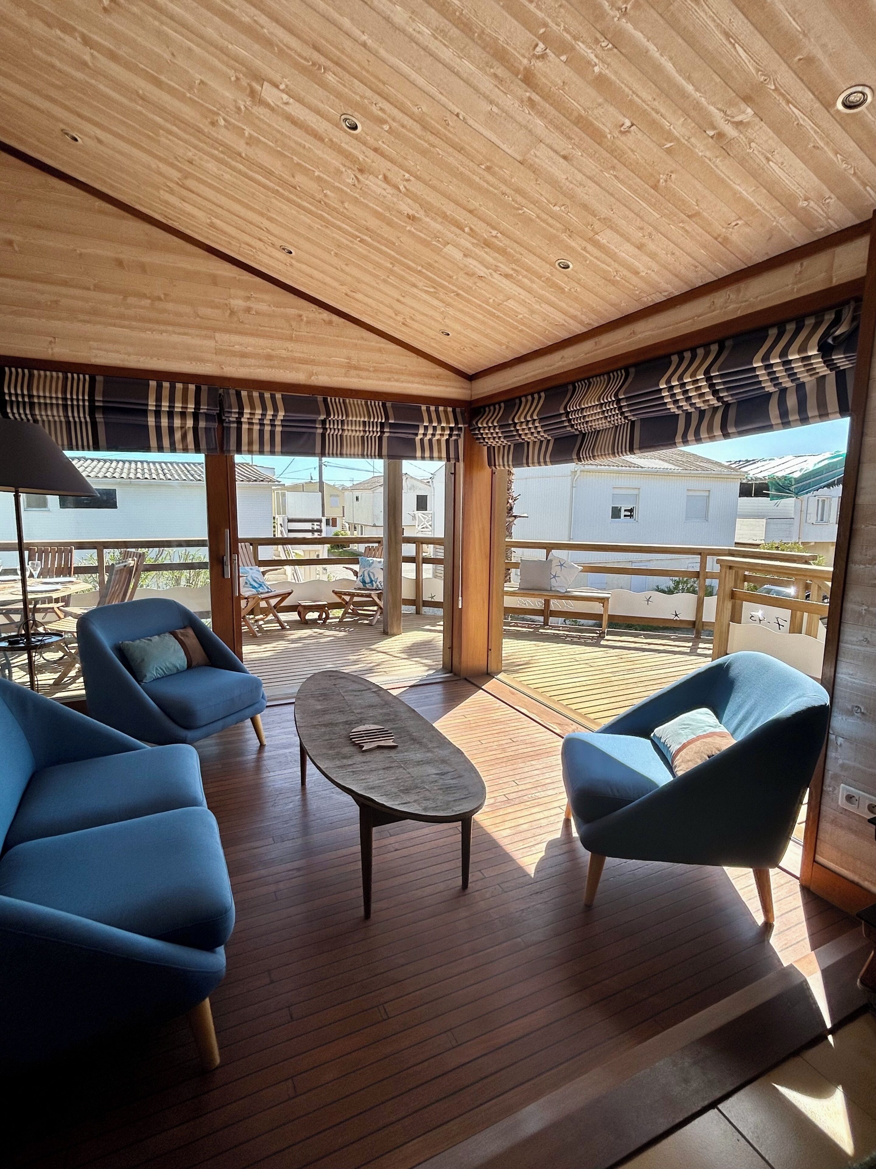 Een modern interieur met een houten plafond, blauwe bekleden stoelen, een kleine tafel en uitzicht op het buitengebeuren.