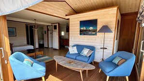 Una stanza con pavimento in legno, un divano blu, un tavolino da caffè e una lampada.
