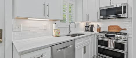 A modern kitchen with white cabinets, stainless steel appliances, a double oven, and a microwave.