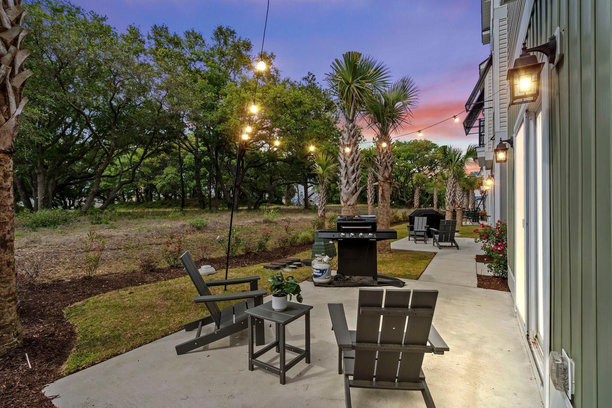 An outdoor patio with a grill, seating, and string lights.