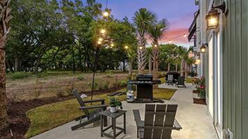 An outdoor patio with a grill, seating, and string lights.