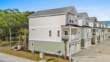 A row of townhouses with a front porch, a small garden, and a clear sky.