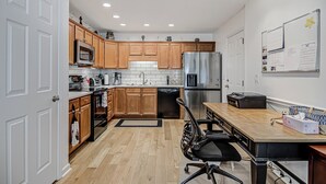 Eine moderne Küche mit Holzschränken, Edelstahlgeräten, einem Essbereich mit Tisch und Stühlen sowie einer Tafel an der Wand.
