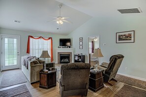 Ein Wohnzimmer mit Kamin, Deckenventilator und Fernseher.