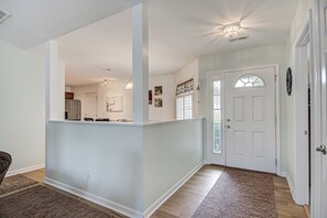 A spacious hallway with a kitchen area, a door with a decorative glass panel, and a rug on the floor. - Adorable 2 Bedroom One Story Townhouse with Garage (High Point)