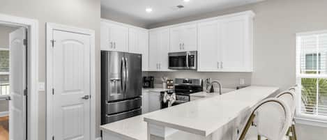 A modern kitchen with white cabinetry, stainless steel appliances, and a central island.
