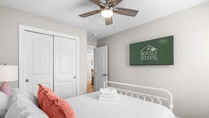 A bedroom with a bed, a ceiling fan, a wall-mounted TV, and a door leading to another room. - The Pink Panther-ocean Side-pet Friendly (Myrtle Beach)