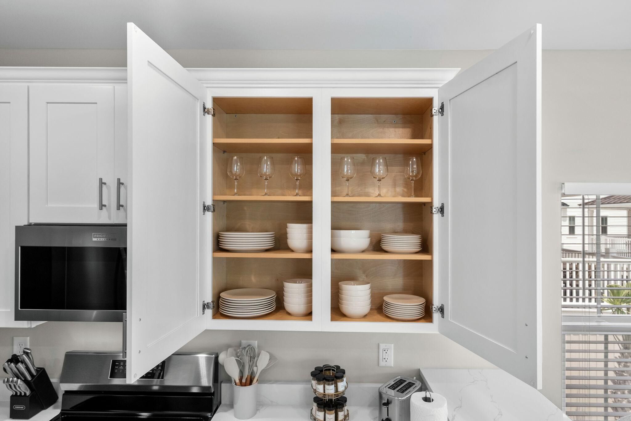 A kitchen with white cabinets, a microwave, a toaster, and a window with a view.