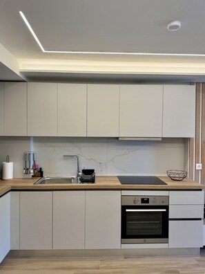 Una cocina moderna con horno empotrado, pileta de acero inoxidable y encimera de madera.