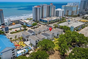 Zona hotelera costera con varios edificios, una playa y un parque infantil.