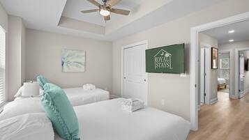 A hotel room with two beds, a ceiling fan, a painting, and a sign that reads "ROYAL STAYS".