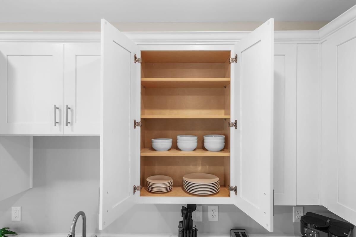 A kitchen with white cabinets, a built-in oven, and a sink.