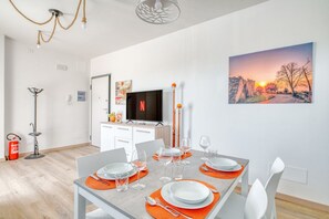 Ein Essbereich mit einem Tisch für vier Personen, einem Fernseher und einem Sonnenuntergangsbild an der Wand.