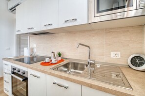 Eine moderne Küche mit Spüle aus Edelstahl, integriertem Backofen und Mikrowelle.