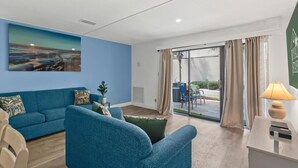 Uma sala de estar moderna com um sofá azul, uma poltrona verde e um quadro grande na parede.