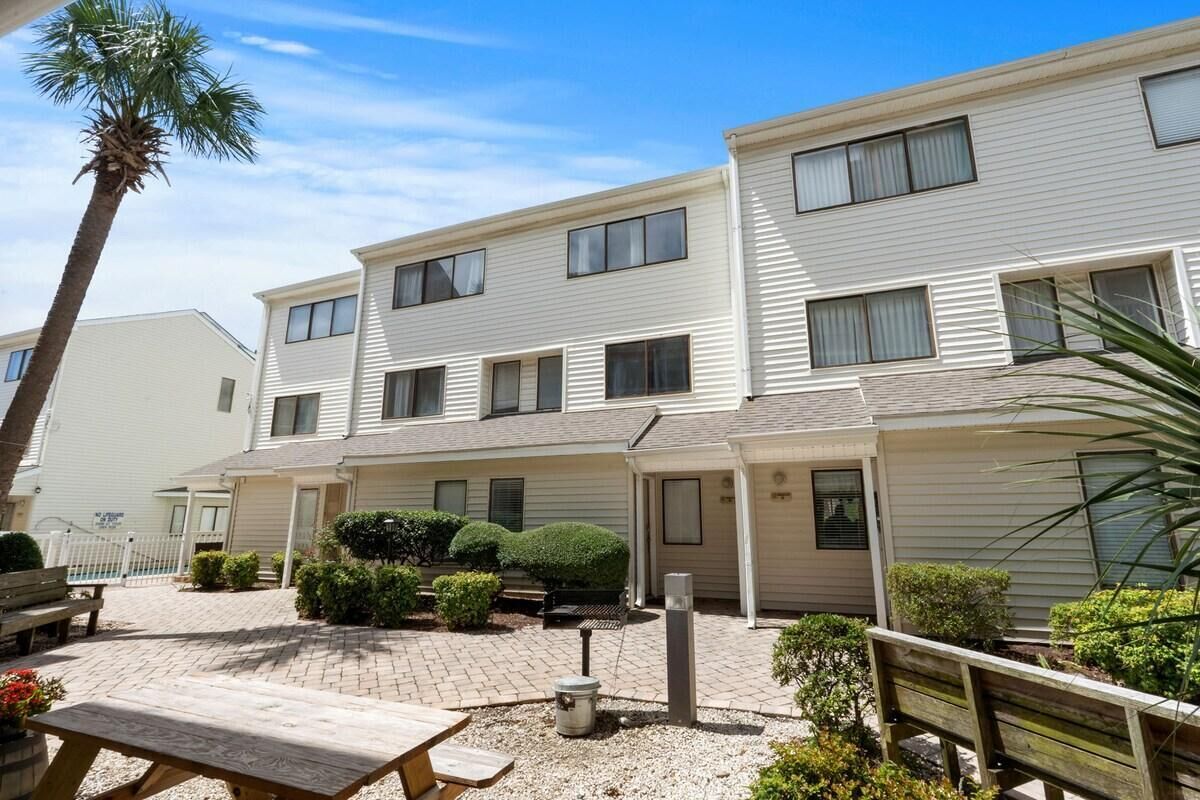 A two-story building with a patio area, outdoor seating, and a small garden.