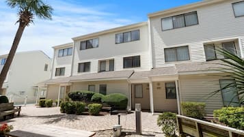 A two-story building with a patio area, outdoor seating, and a small garden.