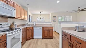Una cocina moderna con armarios de madera, microondas integrado, estufa y lavavajillas.