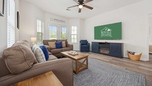 A living room with a sofa, armchair, coffee table, fireplace, and a television mounted on the wall. - Myrtle Golf Escape At Legends-pool-pet Friendly (Myrtle Beach)