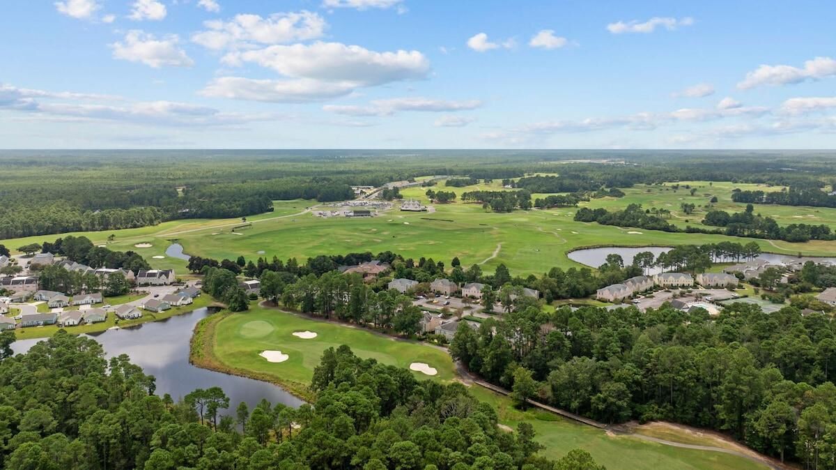 Un campo de golf con varios hoyos, un lago y edificios residenciales.